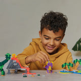Young child building a dinosaur surrounded by other assembled pieces like the volcano and oasis.
