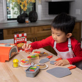 a young child shaking pretend peppers onto their pretend pizza.