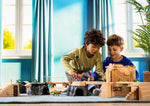 Two kids in a blue room playing with the action figure and dinosaur in the temple playset.