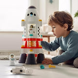 Young child playing with the rocket, an astronaut figure, two loose screws, and the drill are lying nearby.  