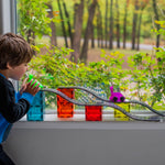 a child playing with toy blocks and racetrack on a window sill