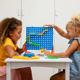 Two young girls testing their marble run creation, various other parts scattered about the table.